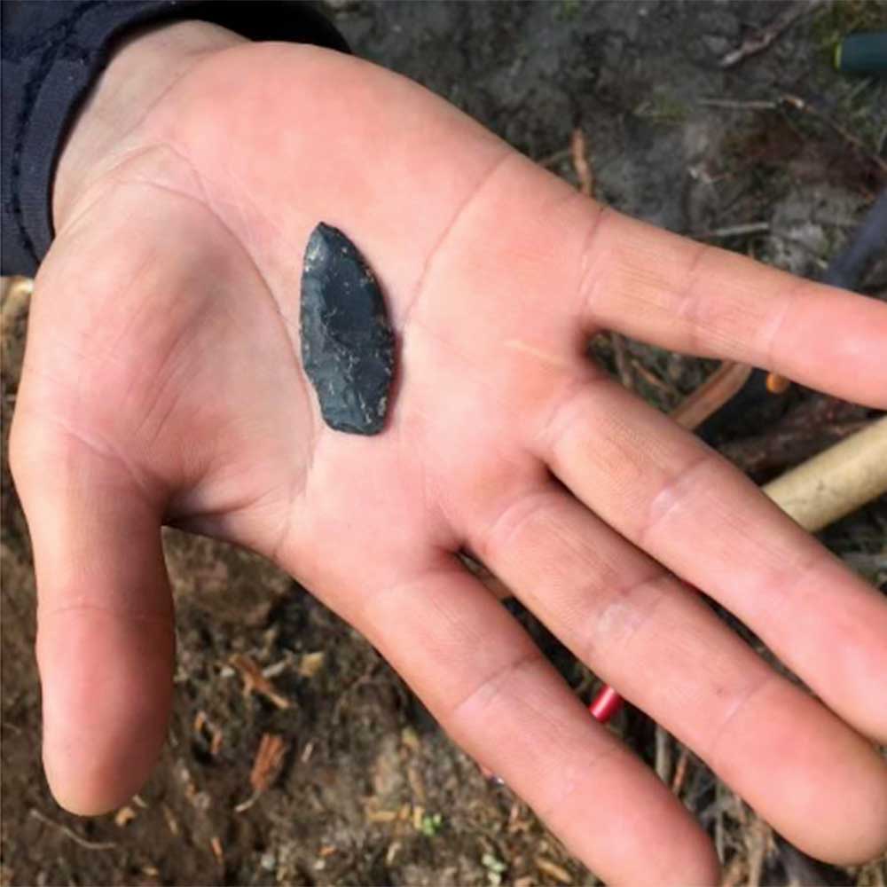 archaeology - hand with a spear head in it